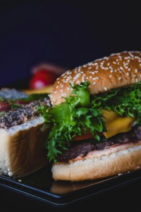 Delicious cheeseburger with lettuce and tomato served on a dark plate.