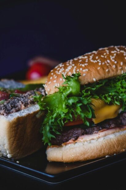 Delicious cheeseburger with lettuce and tomato served on a dark plate.