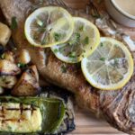 Whole roasted fish with lemon slices and grilled vegetables